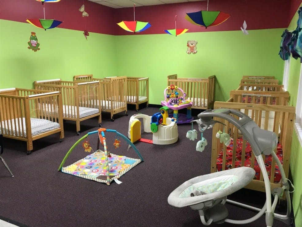 Room with multiple cribs and baby play equipment