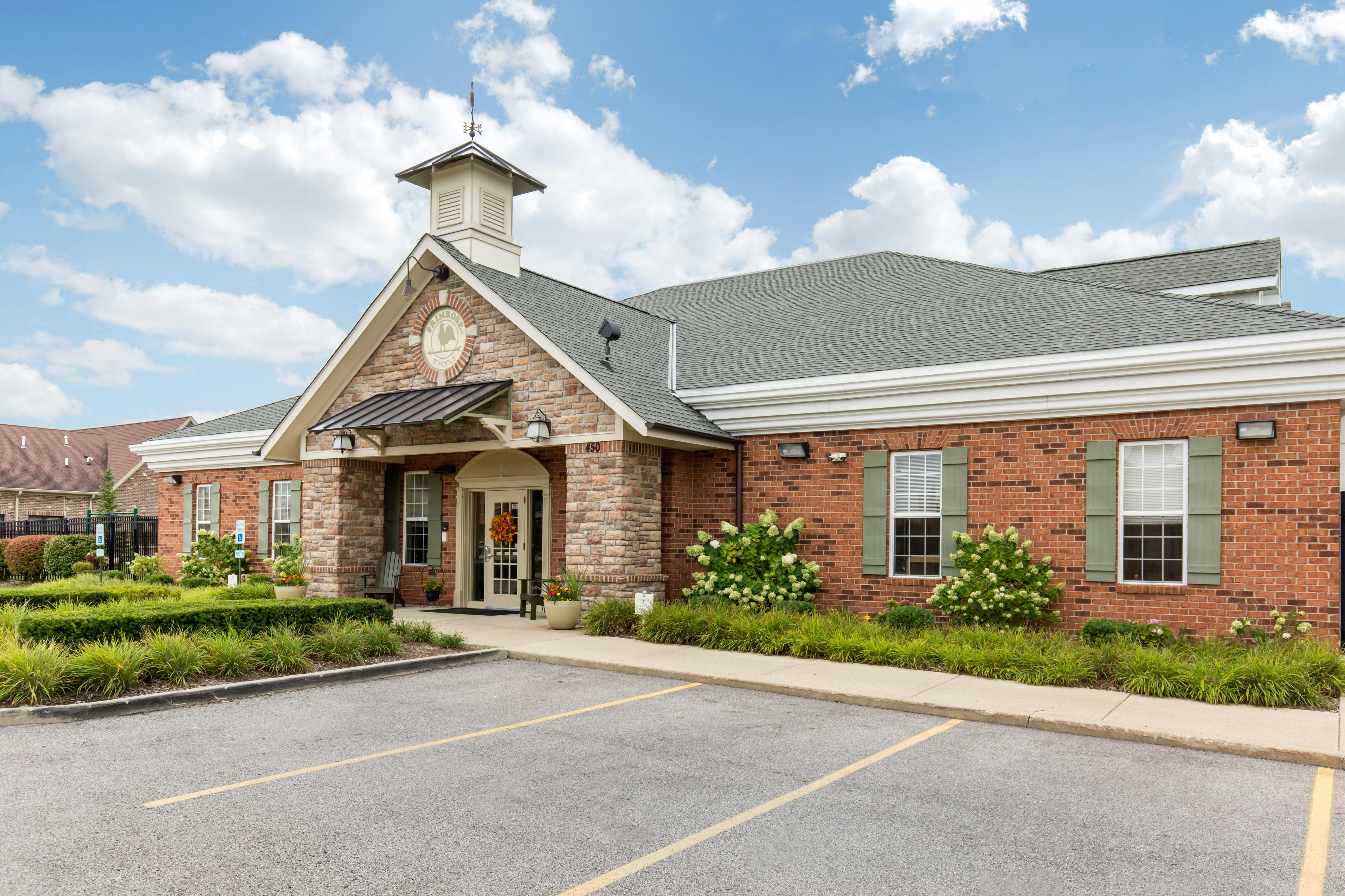 Brick building with stone entrance and small cupola, "PRIMROSE SCHOOLS" text