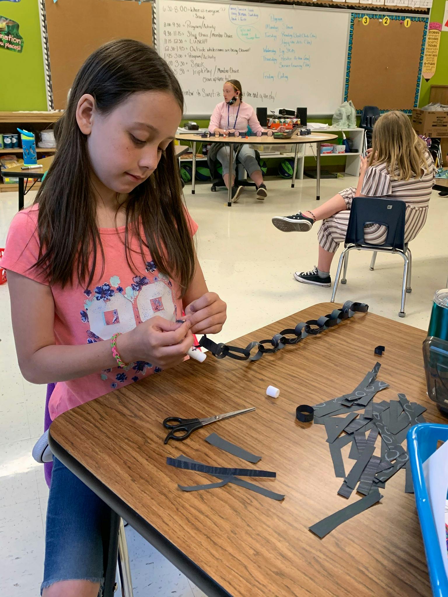 Child making a paper chain in a classroom