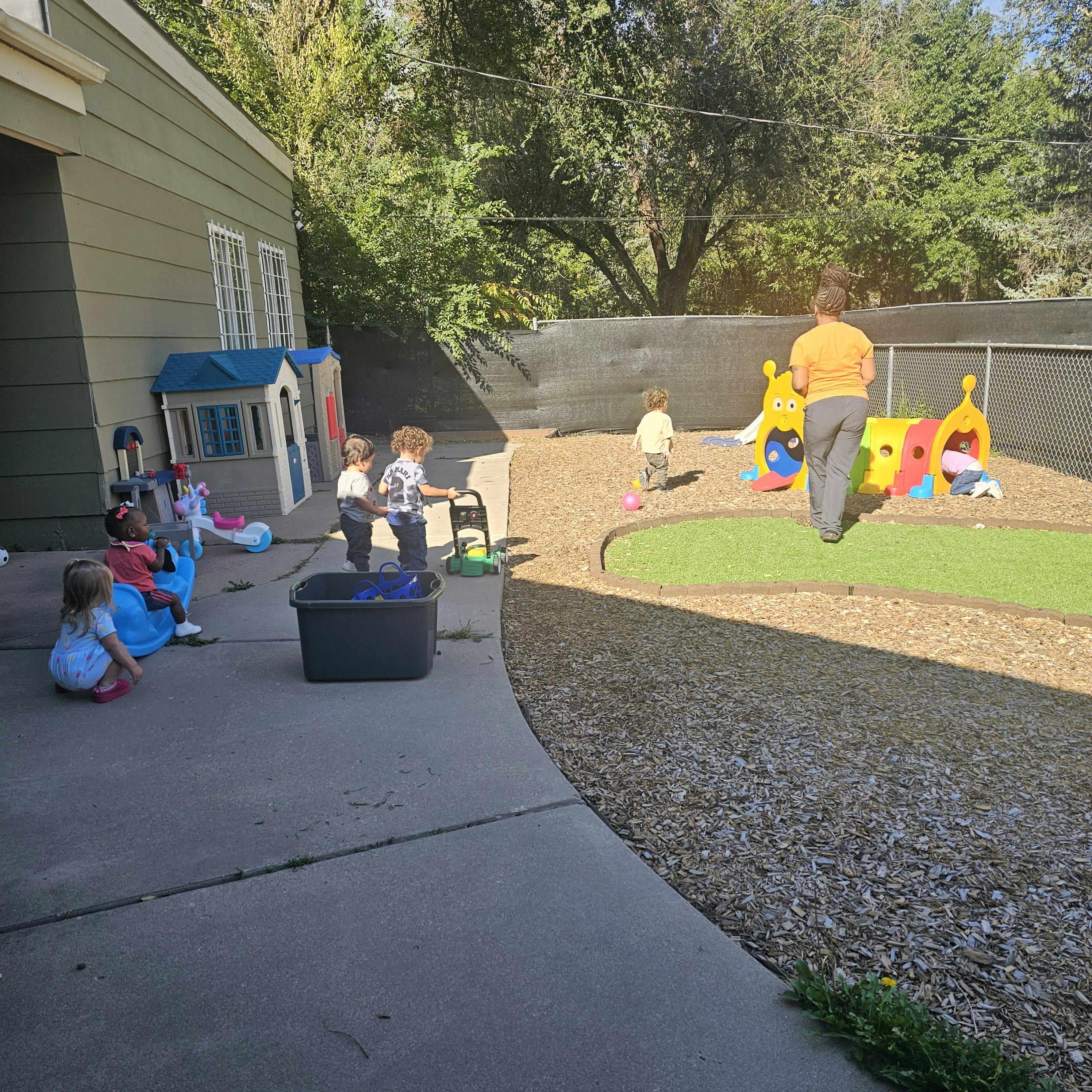 Adult and children playing in an outdoor area with play structures