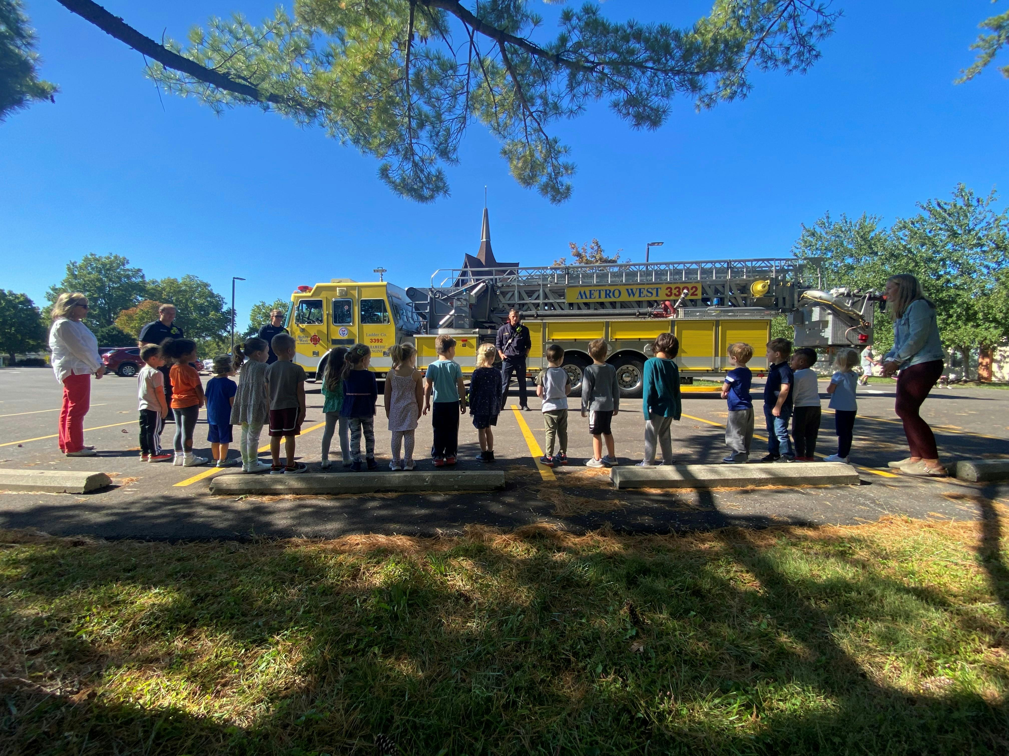 Adults and children standing in a line in front of a fire truck
