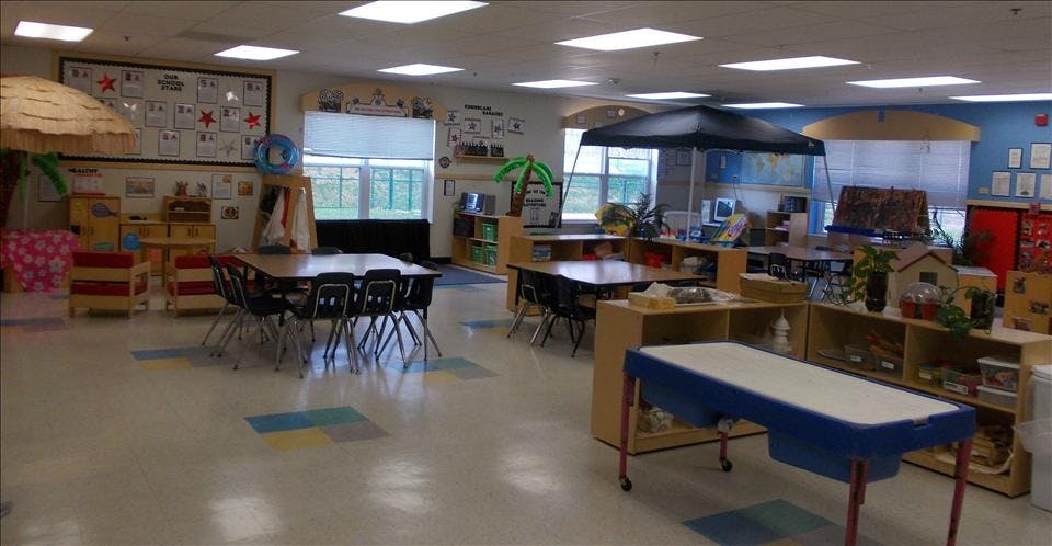 Colorful preschool classroom with various activity stations and small tables