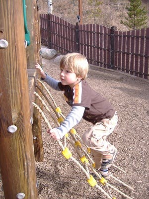 Child climbing a rope ladder on a playground