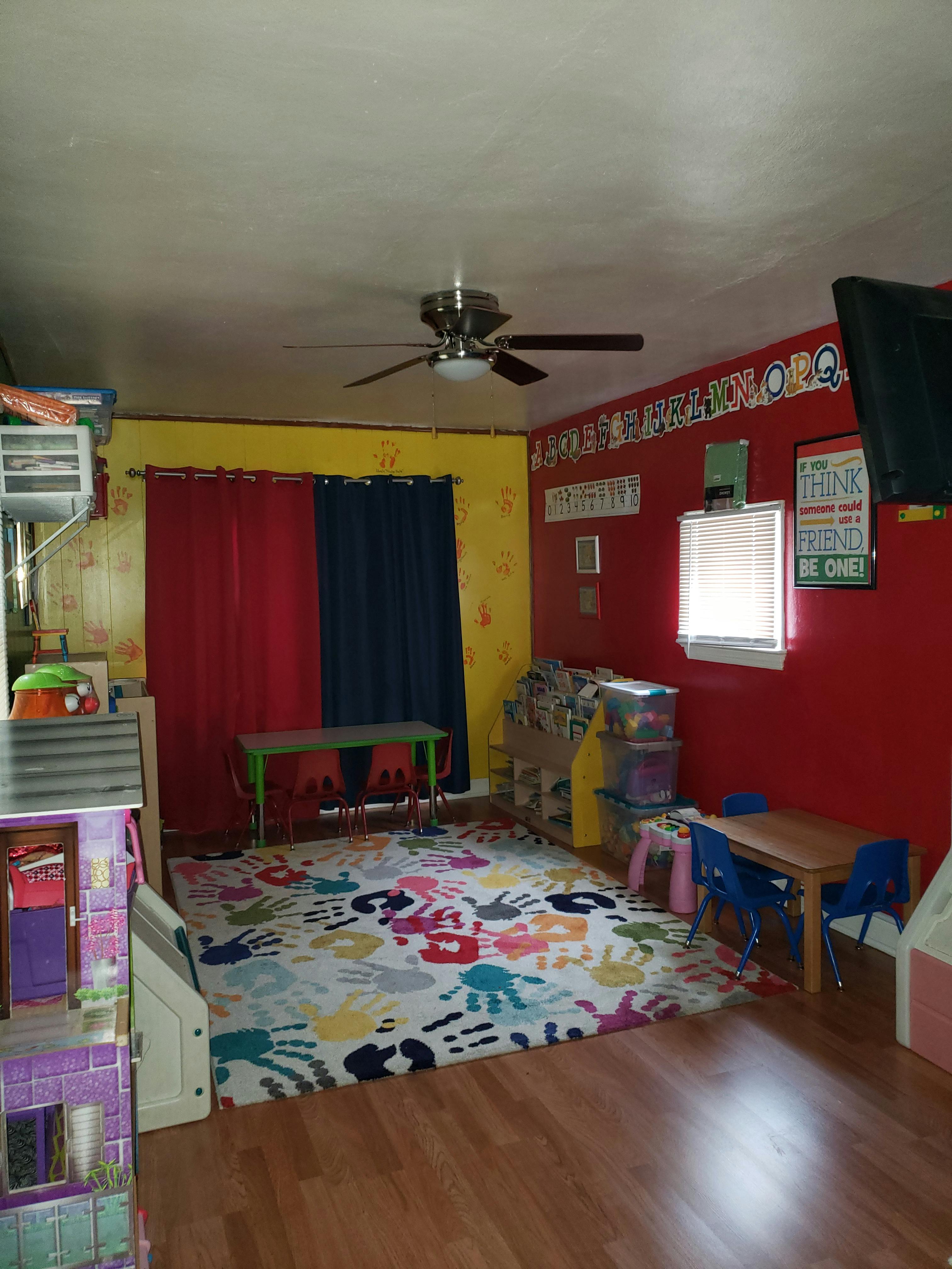 Playroom with colorful walls, a ceiling fan, and a rug with handprints