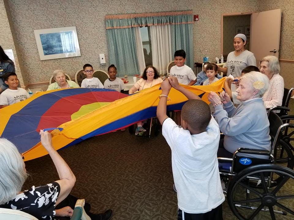People of different ages holding a colorful parachute