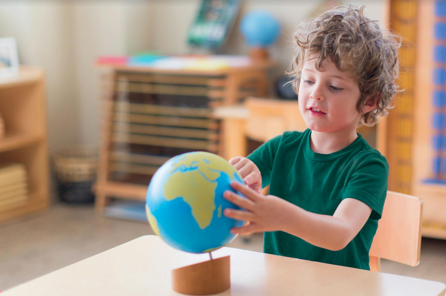 Child touching a globe on a table