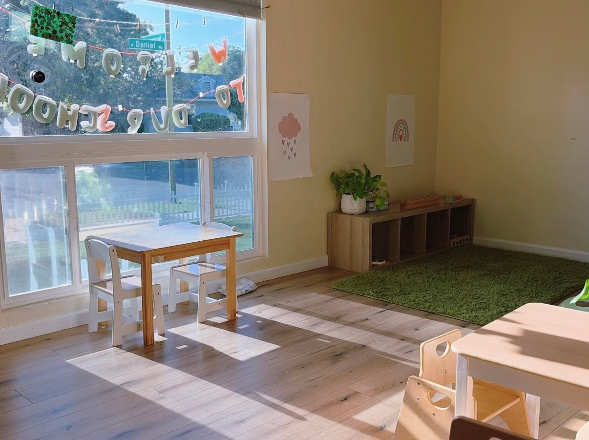Sunny classroom with small tables, chairs, and play mats