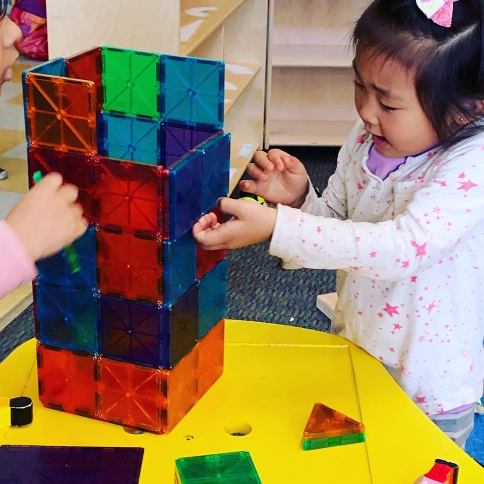 Two children building with colorful magnetic blocks