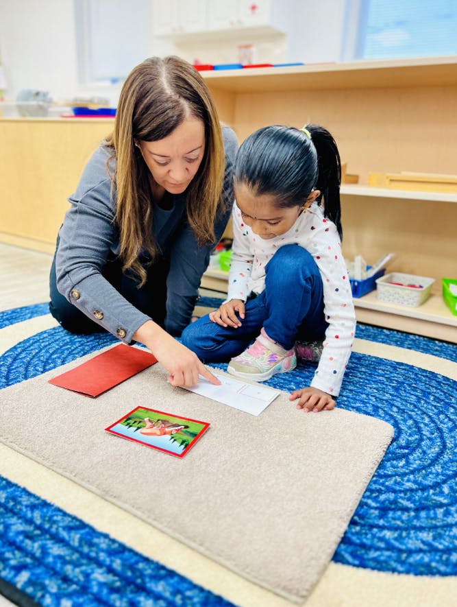 Adult and child on floor working with learning cards