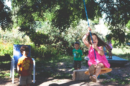 Child in pink dress swinging on a rope swing outdoors