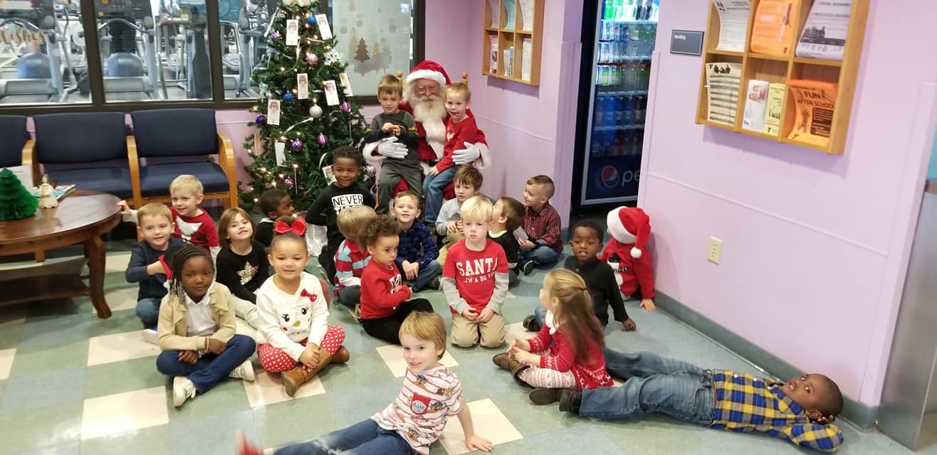 Santa Claus sitting with a group of children around a Christmas tree