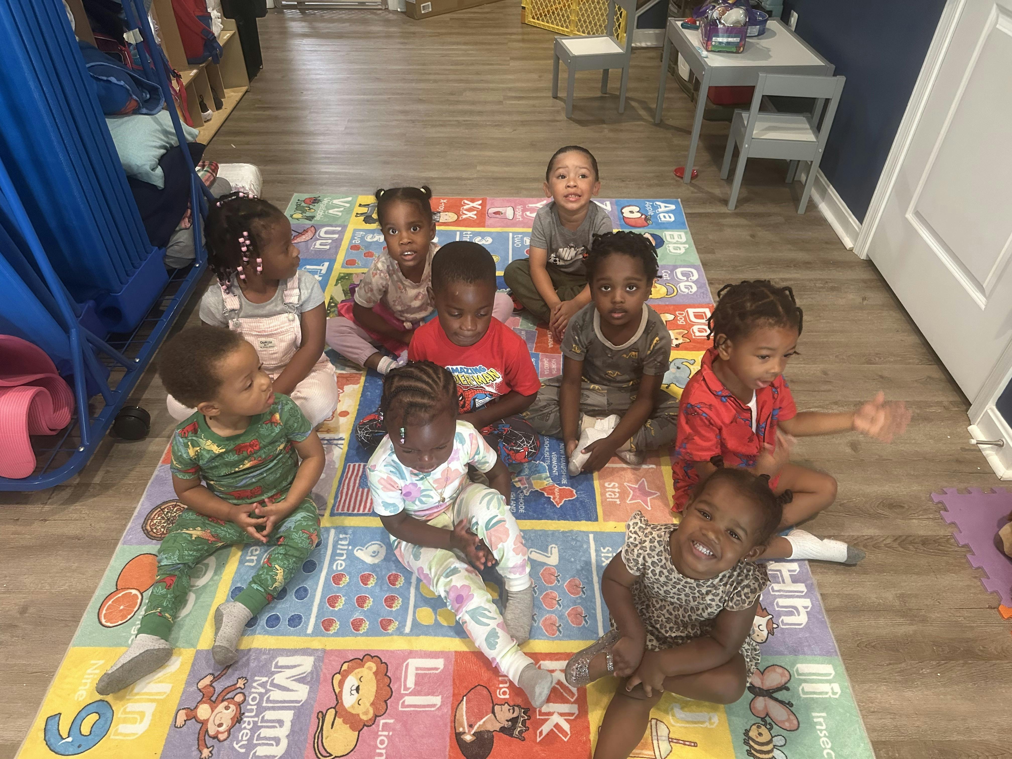 Group of children sitting on a colorful mat in a classroom