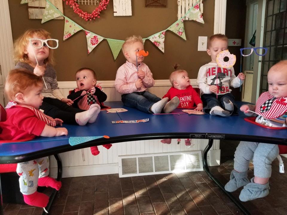 Six children sitting around a blue table