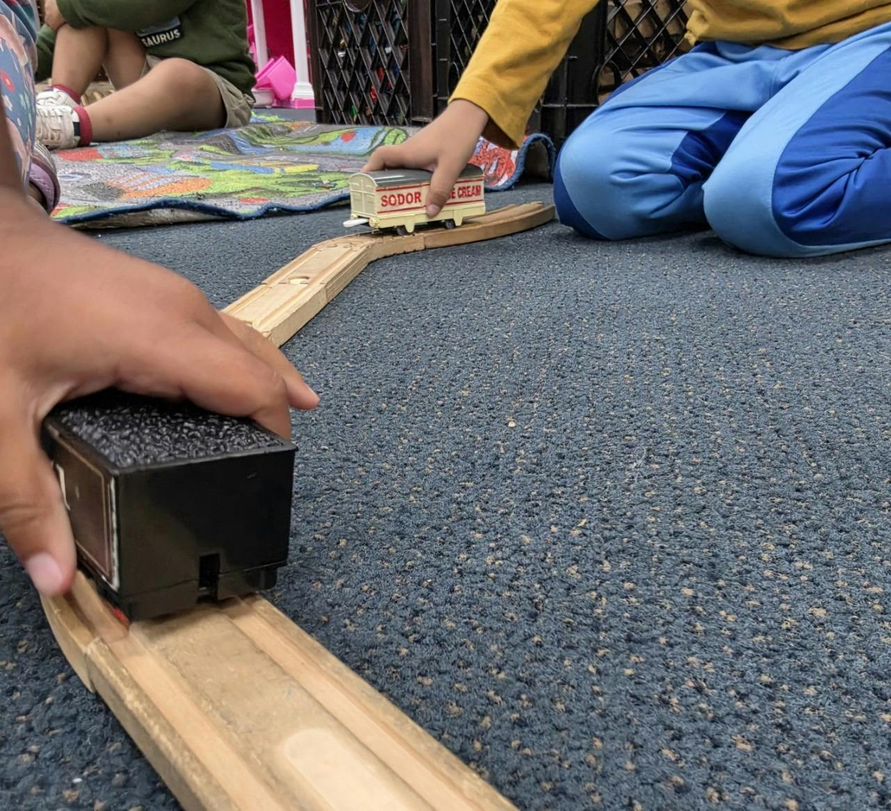 Children playing with a toy train on wooden tracks