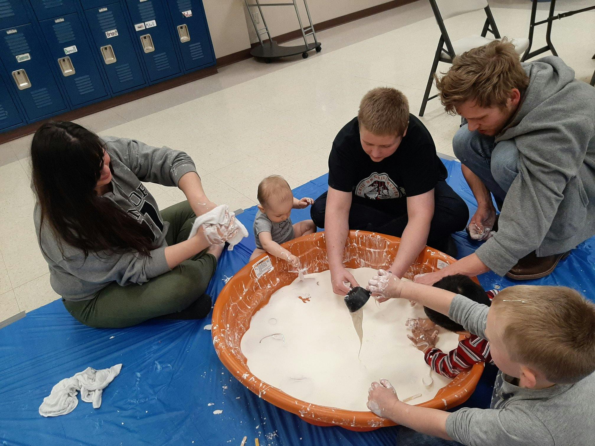 People and children playing in a large tub of white powder