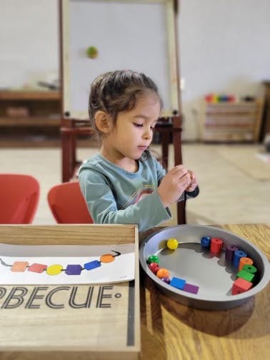 Child playing with colorful beads and shapes at a table