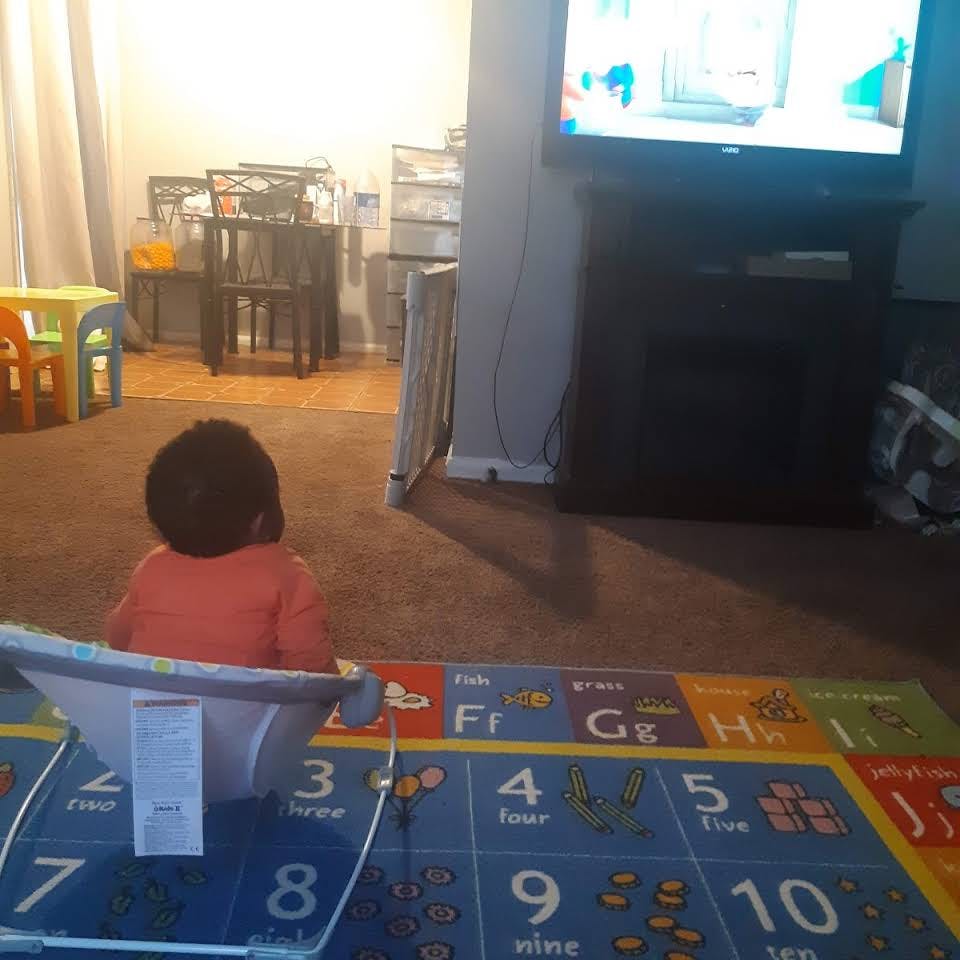 Child sitting on a playmat watching television