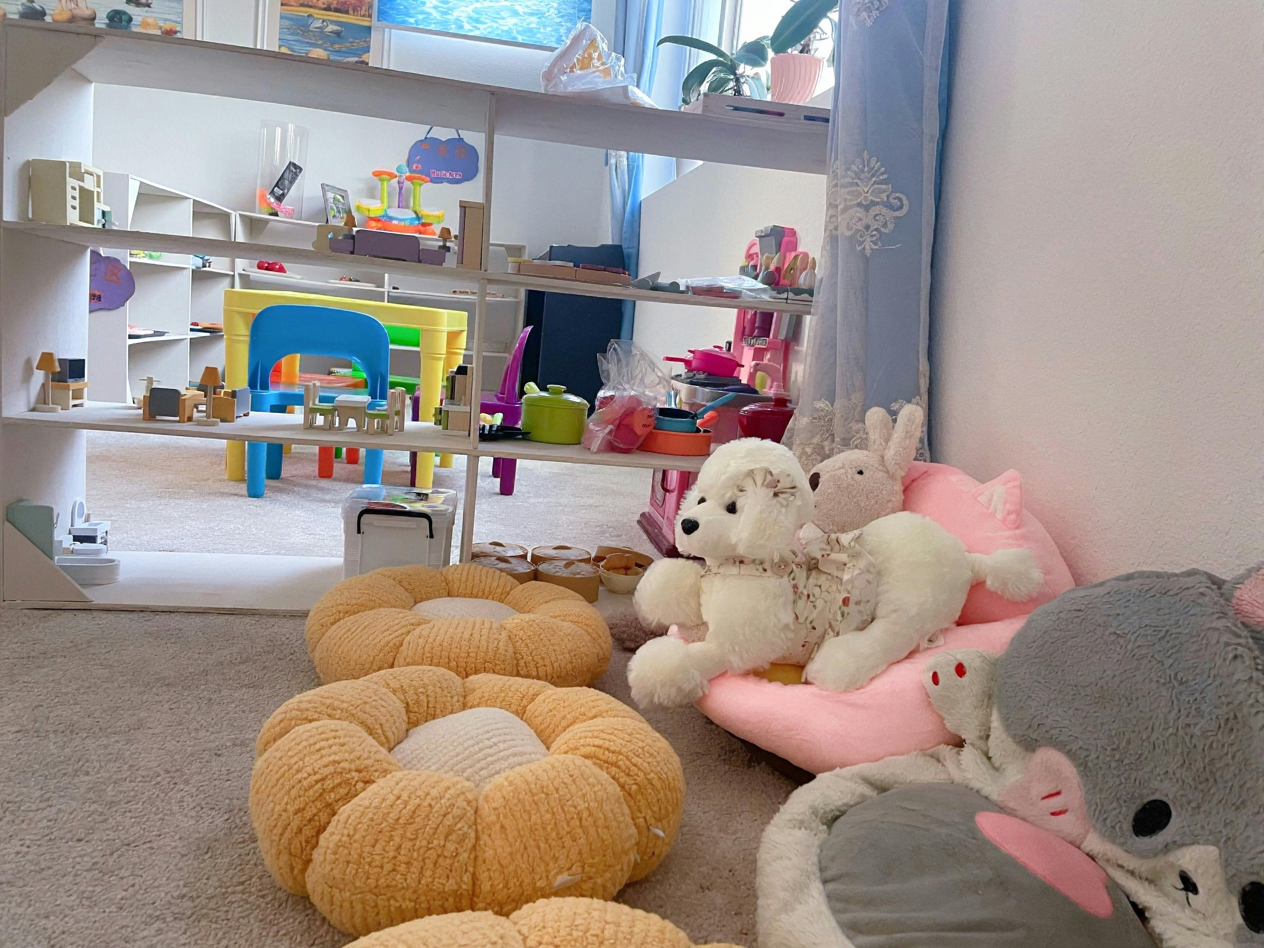 Plush toys on cushions in a playroom with toy shelves and children furniture