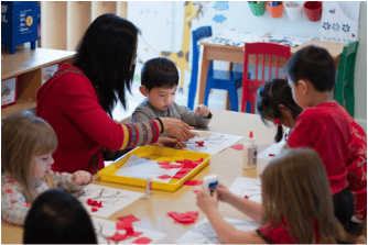 Adult and children at a table doing an art activity