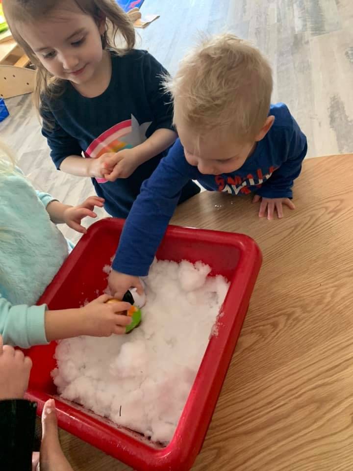 Children playing with white material in a red bin