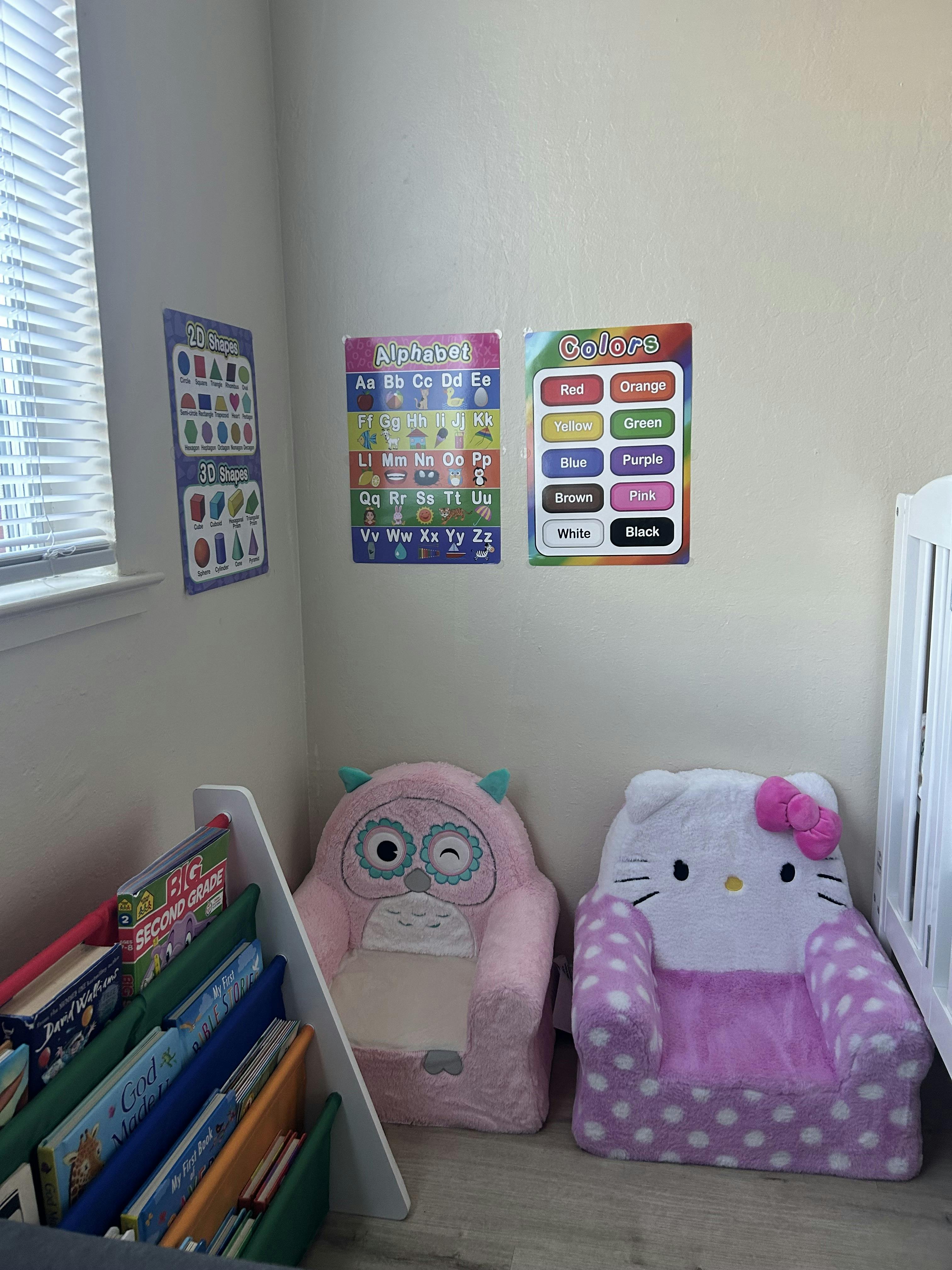 A room with learning posters, two plush chairs, and a small bookshelf