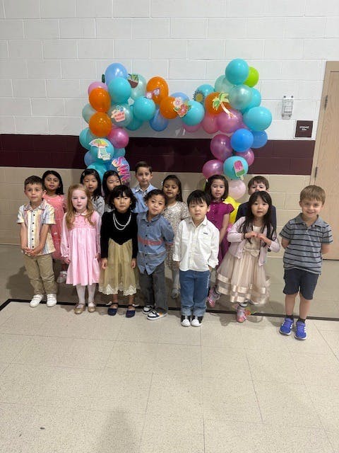 Group of children standing in front of a balloon arch