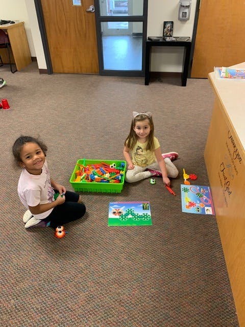 Two children playing with toys on a carpeted floor