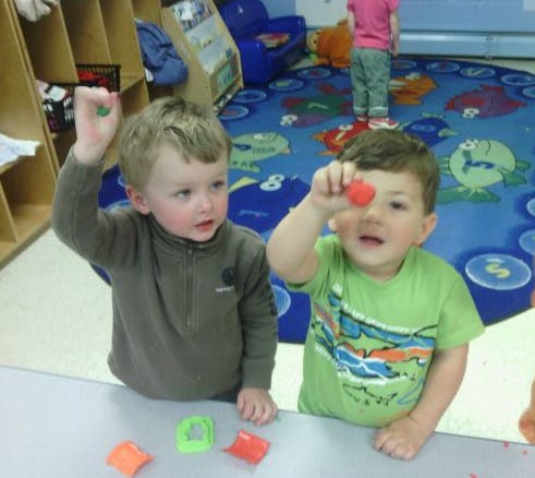 Two children playing with colorful objects at a table