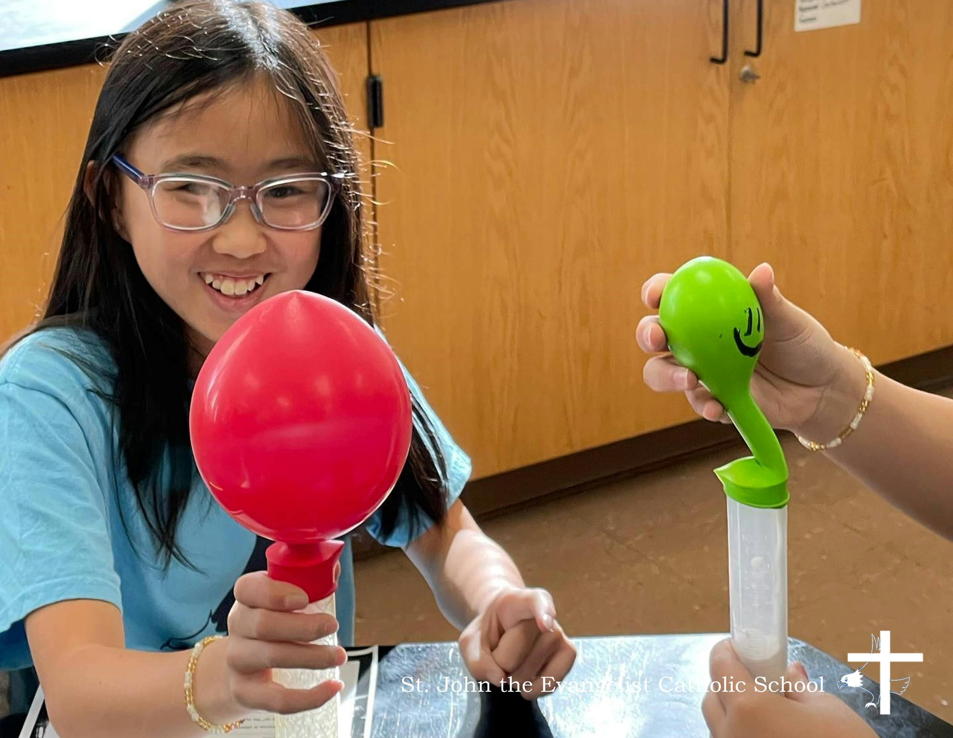 Child holding a red balloon on a stick, another person holding a green one