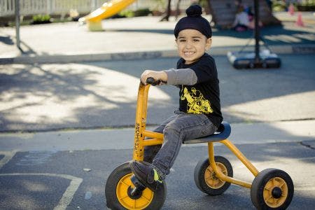 Child riding a tricycle outdoors on a tricycle