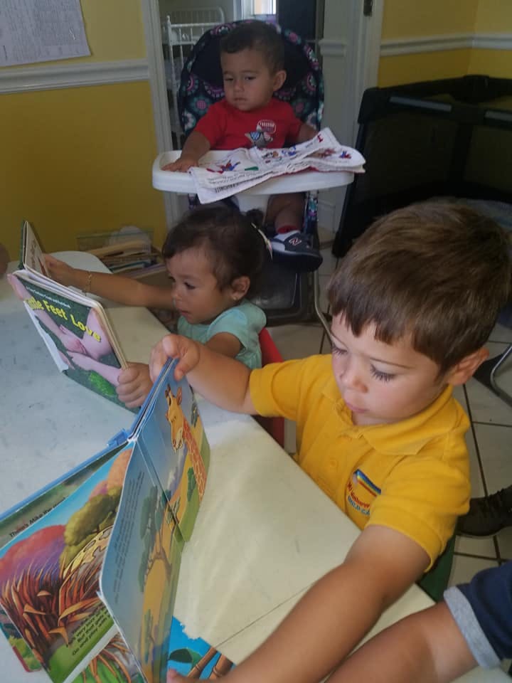 Three children reading books at a table