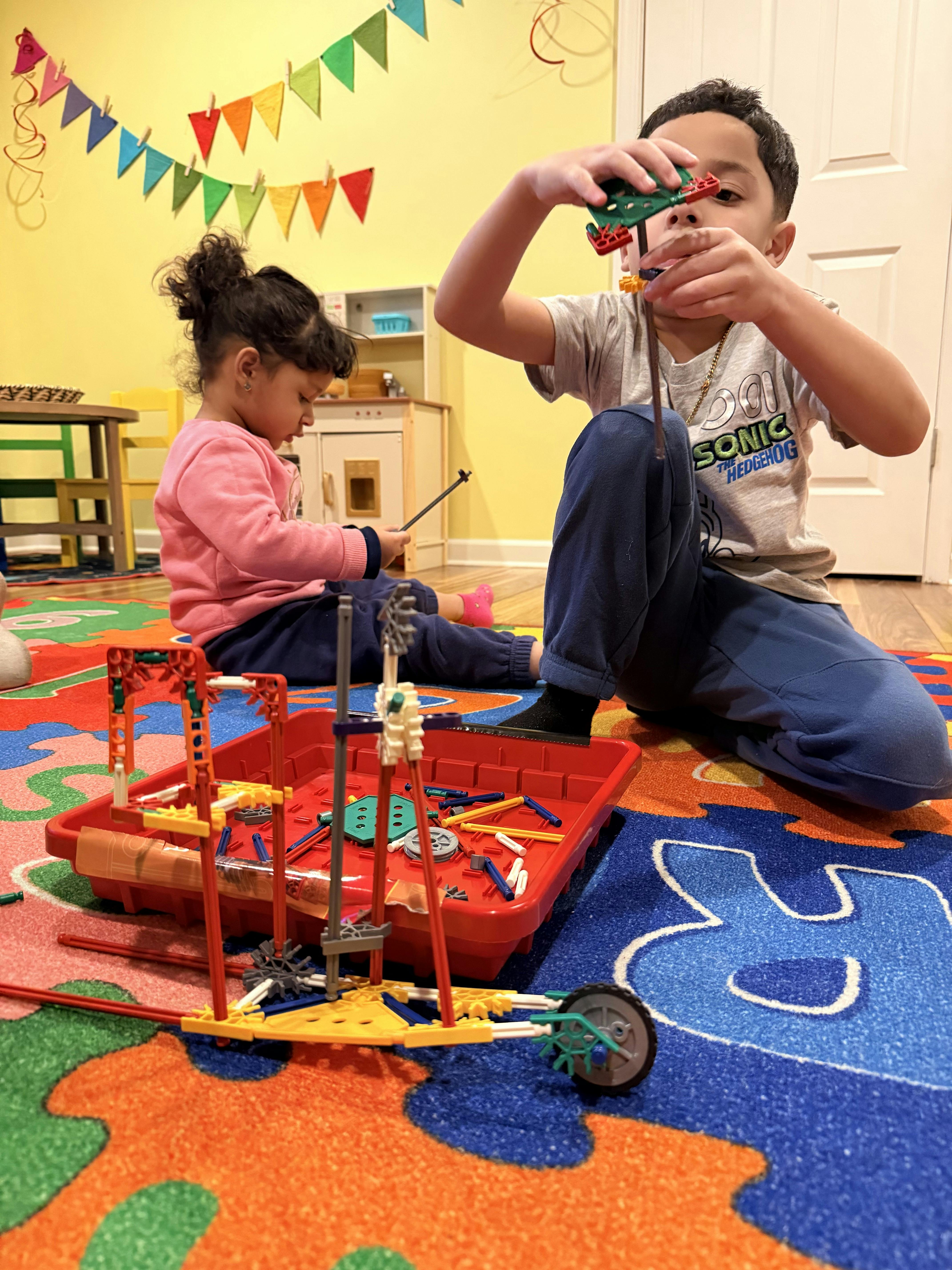 Child building with colorful construction toys as another child watches