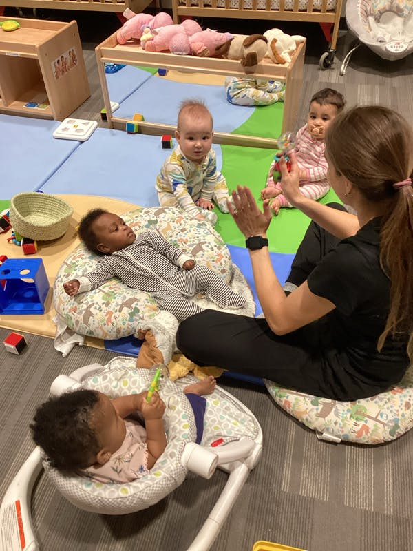 Adult interacting with multiple babies in a play area