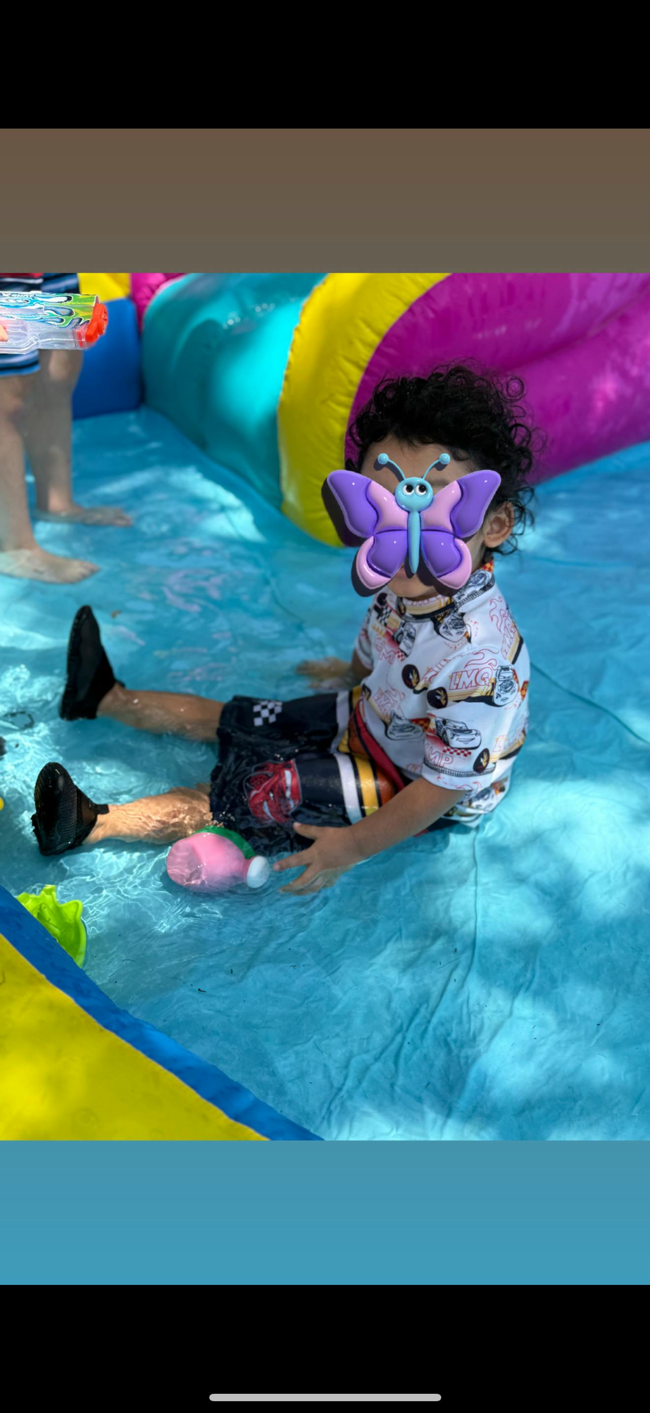 Child sitting in shallow water with an inflatable pool toy