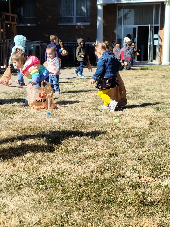 Children on a grassy lawn with one child looking into a bag