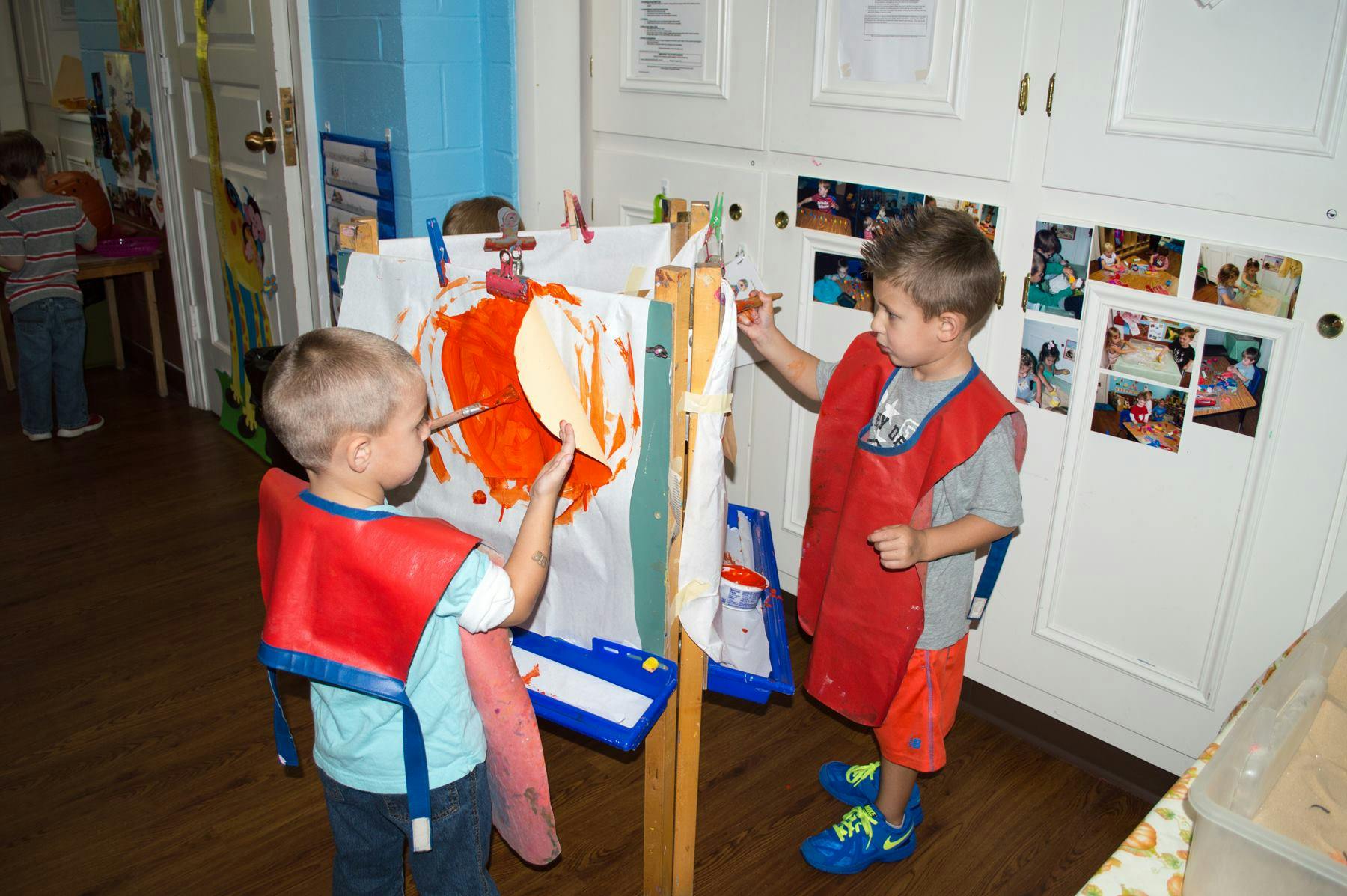 Two children painting at an easel in a classroom