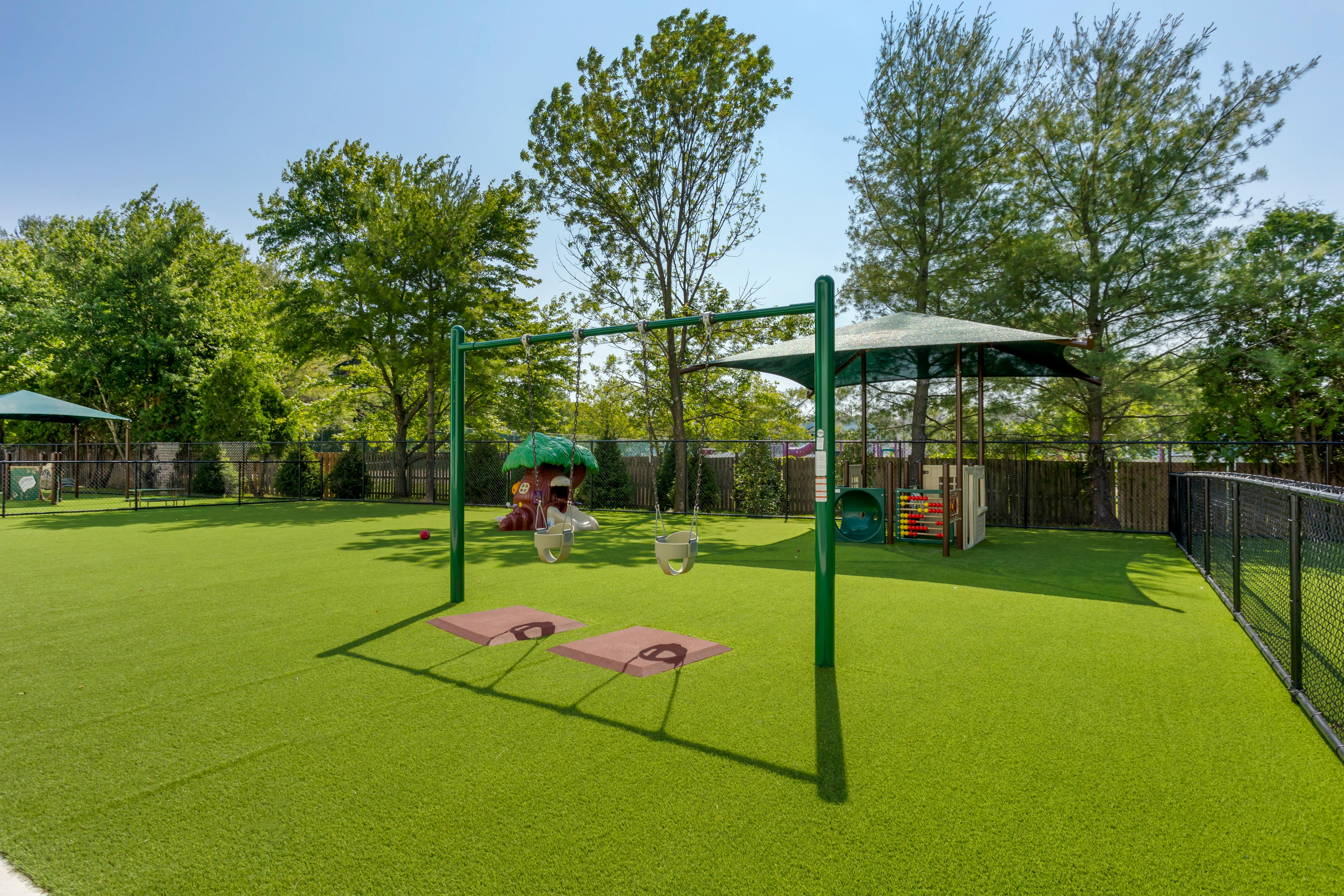 Playground with swings, artificial turf, and a small playhouse