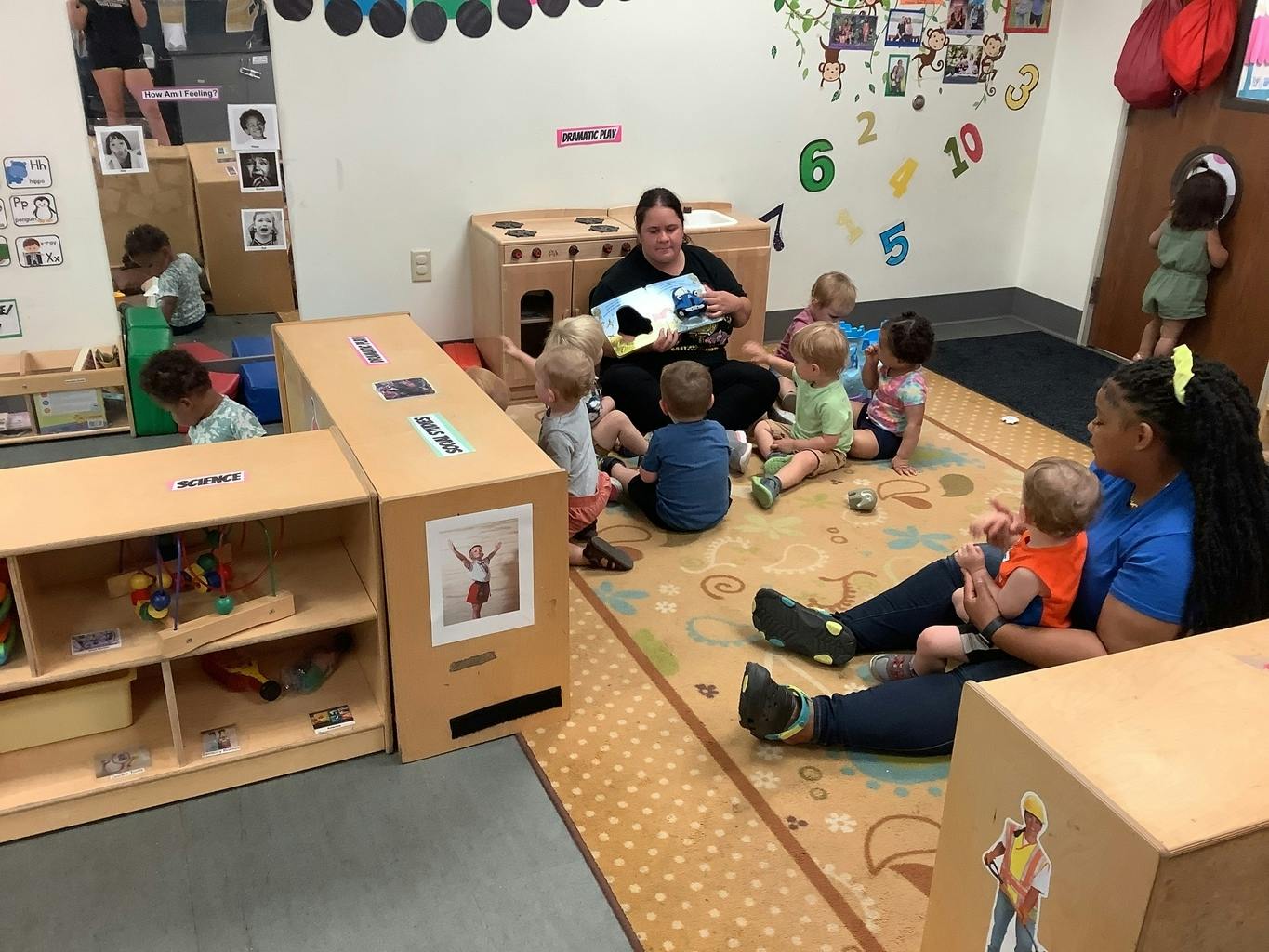 Two adults reading to a group of children in a classroom