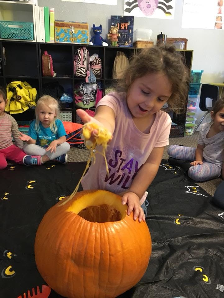 Child removing pumpkin guts from a carved pumpkin