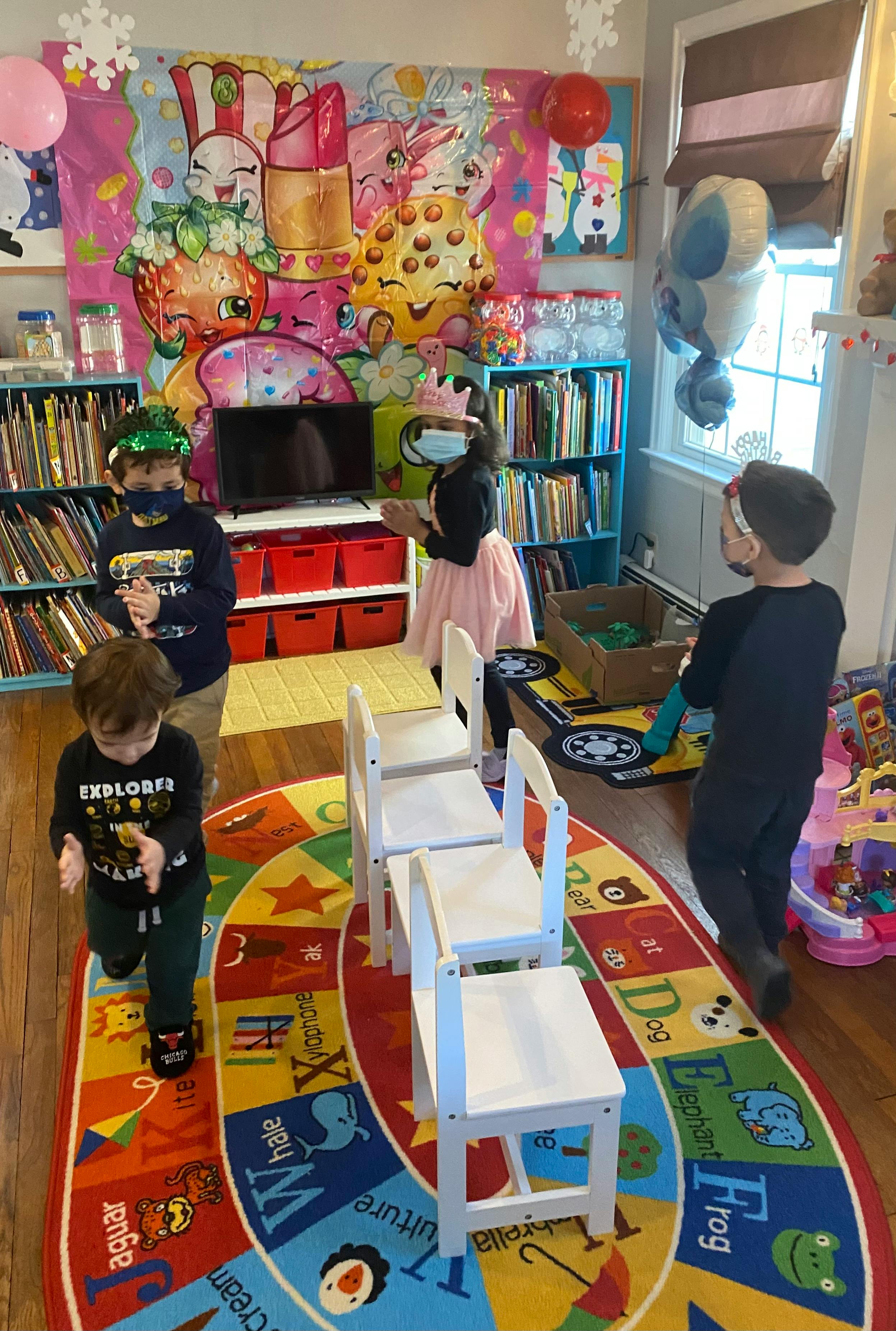 Children in a classroom with bookshelves and a colorful rug