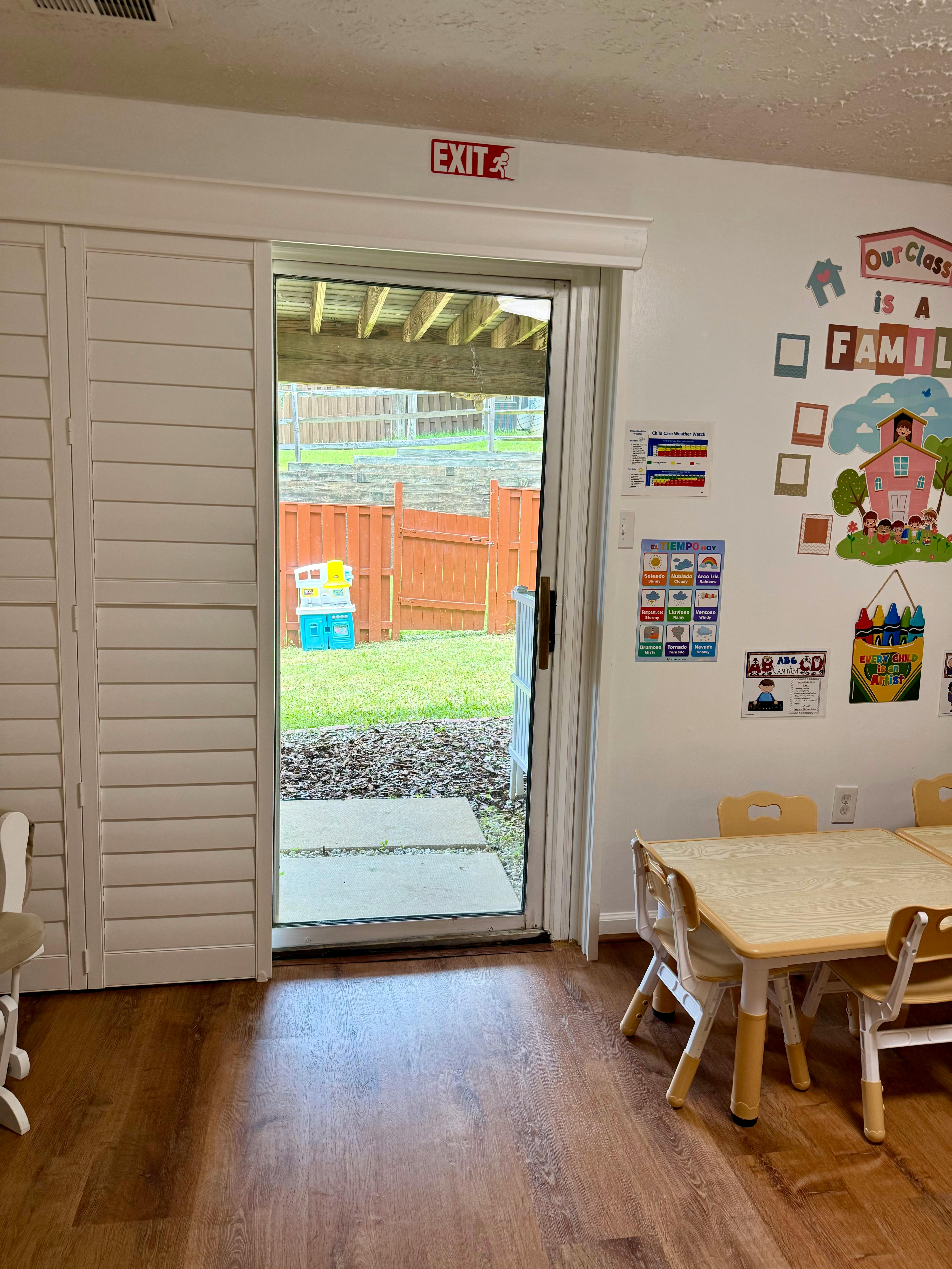 Classroom view through a glass door towards a fenced outdoor play area