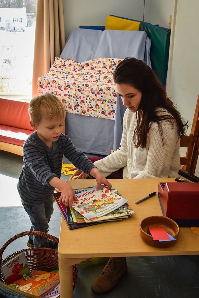 Person and child looking at books on a table