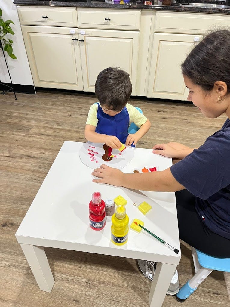 Person and child painting at a table