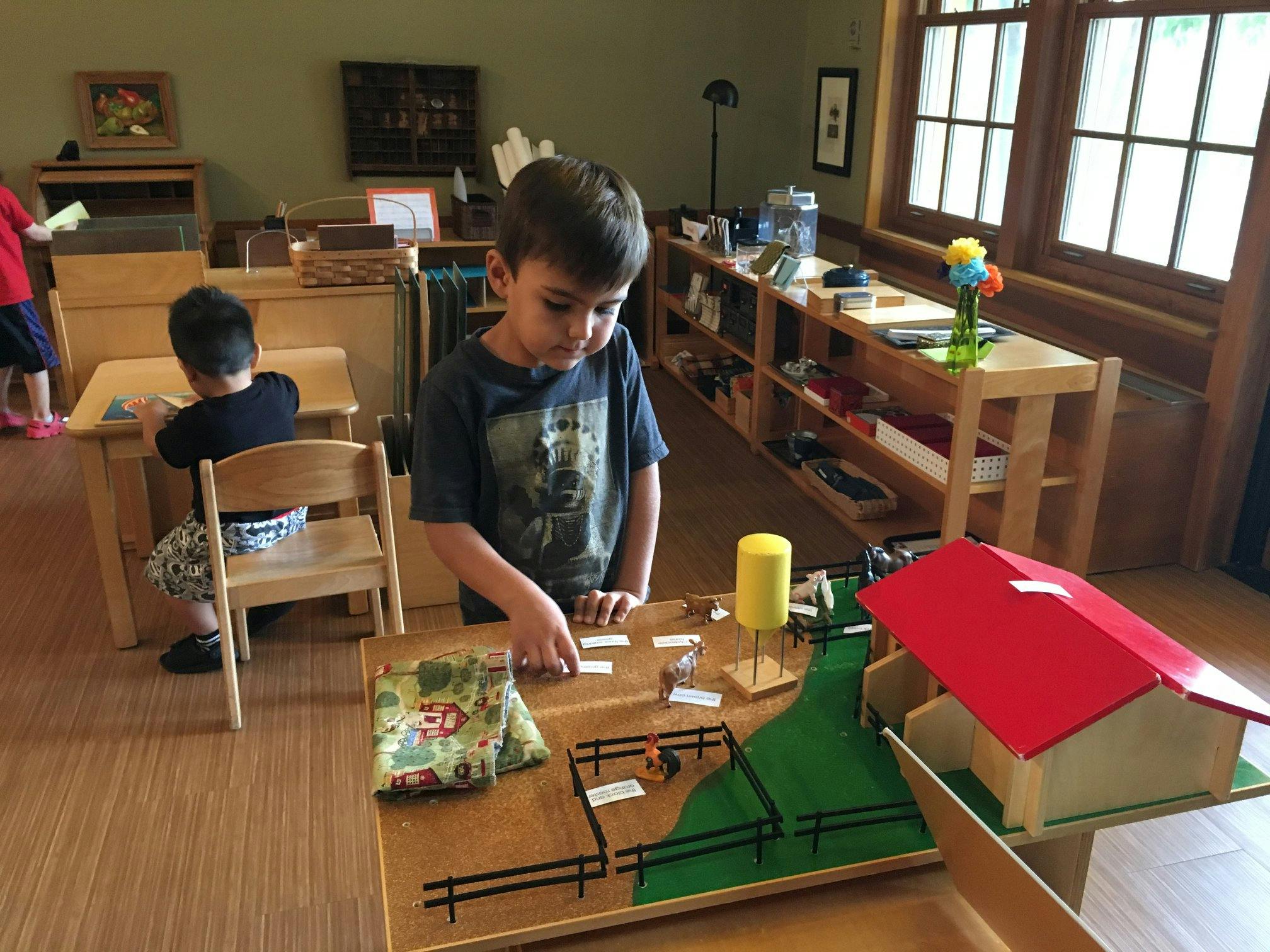 Child playing with a farm set in a classroom