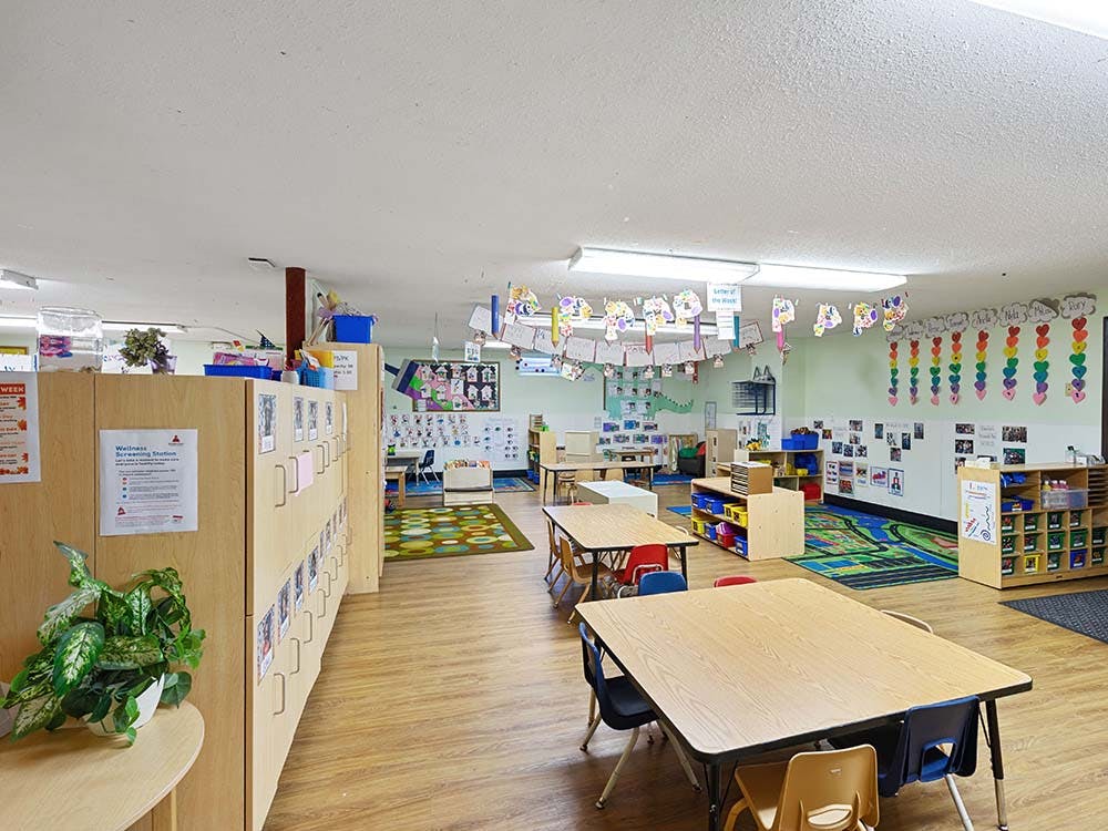 Empty classroom with small tables and chairs, and colorful decorations on the walls