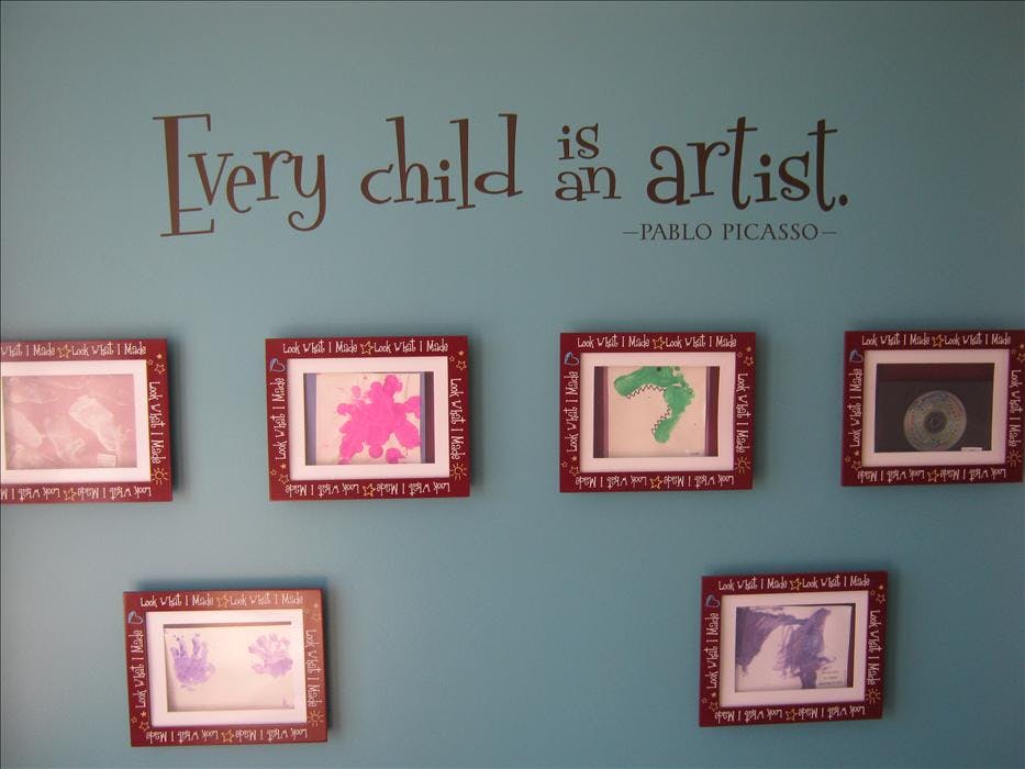 Wall with quote "Every child is an artist" and framed children's artwork