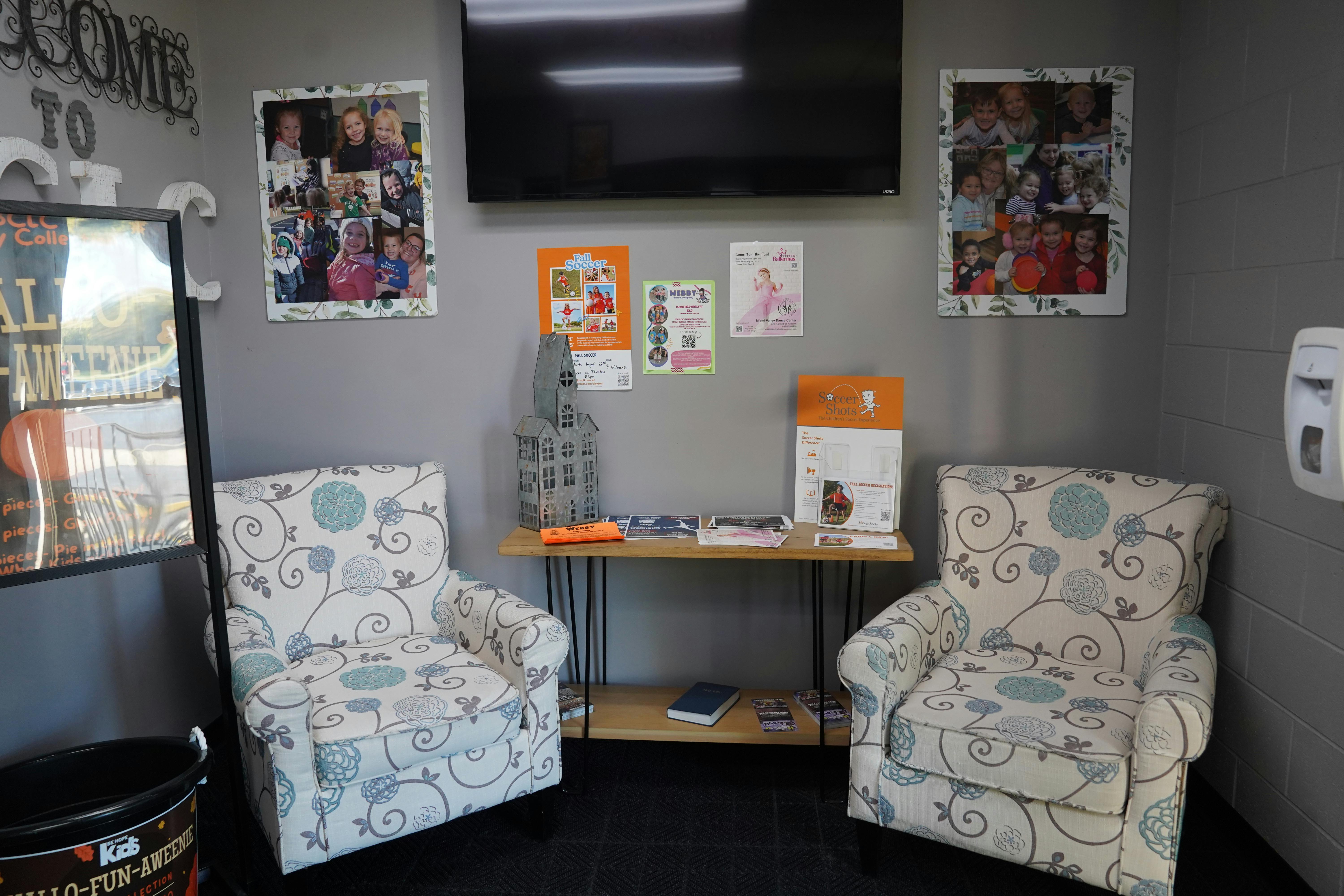 Two patterned armchairs in a waiting area with a table and wall decor