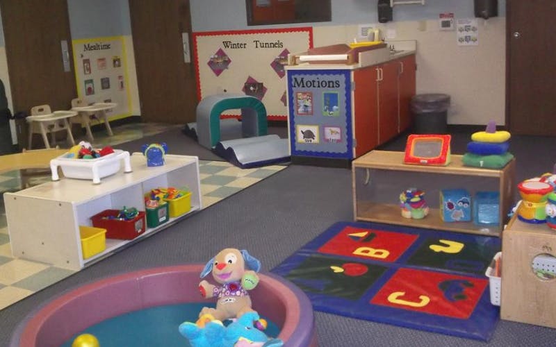 Childcare room with toys, play tunnel, and small tables