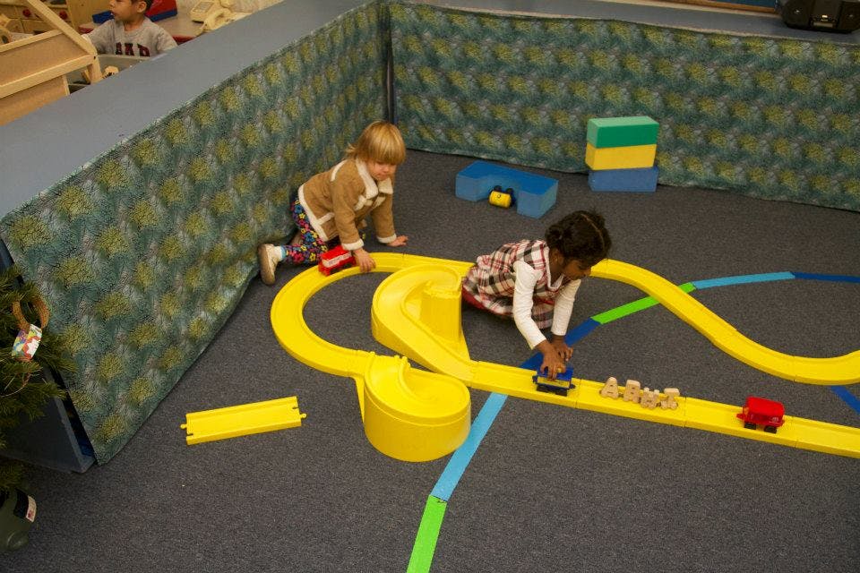 Two children playing with a toy train set on the floor