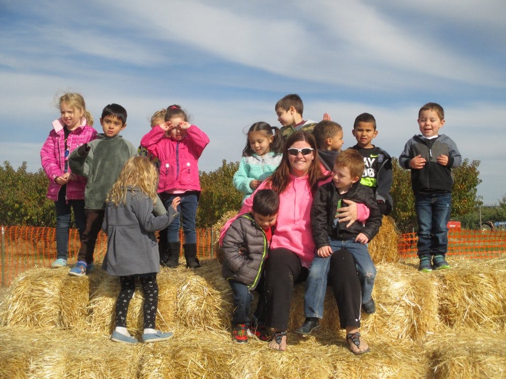 Adult and multiple children on hay bales outdoors